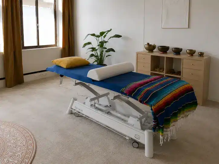 Behandeltafel in een rustige praktijkruimte met natuurlijke tinten, klankschalen en warme inrichting voor energetische en lichaamsgerichte therapie.